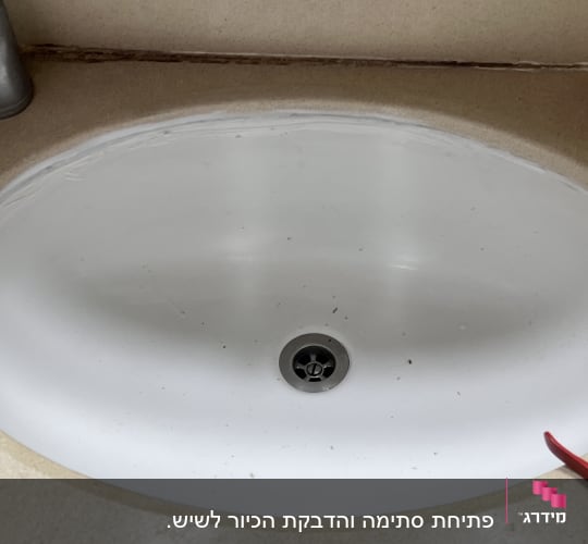 כיור לבן עם ברז וכמה לכלוכים